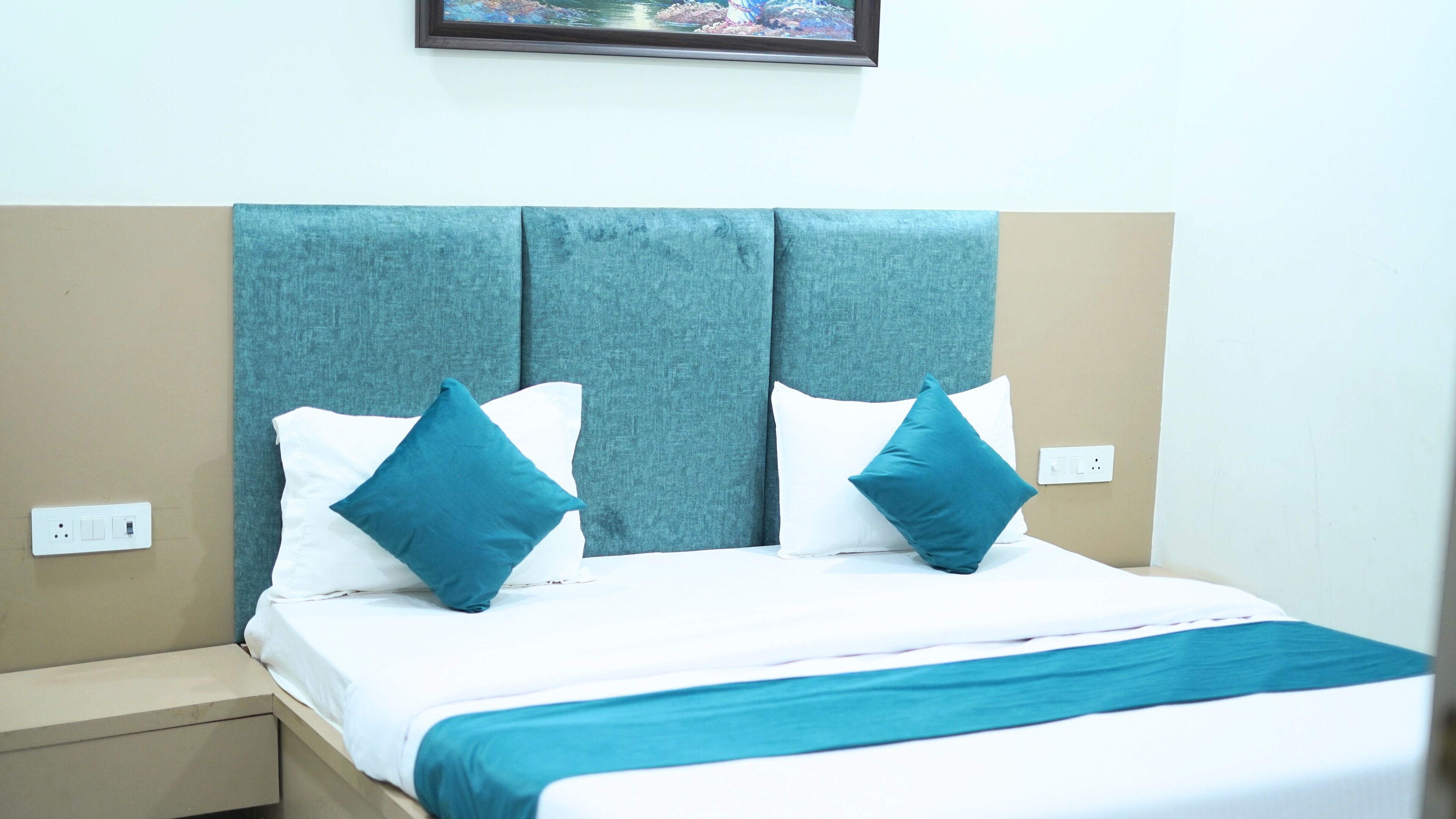 A bed with a teal headboard, white bedding, and two teal pillows.