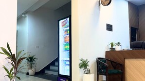 A reception area with a reception desk, a clock, and a refrigerator stocked with beverages. - Hotel Shri Radha Sneh Mathura (Mathura)