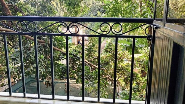 A balcony with a metal railing overlooking a garden with various plants and trees. - Cozy and Affordable  studio in Kasarani, Seasons,near Thika Road, Nairobi (Nairobi)