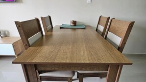 A rectangular wooden table with four chairs, a small table lamp, and a wall-mounted television. - Your Retreat in Roldanillo! (Roldanillo)