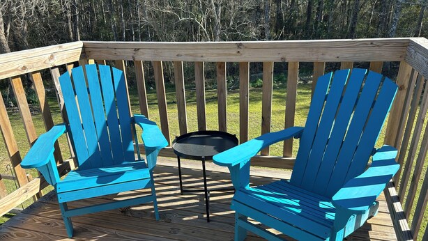 A wooden deck with two blue Adirondack chairs and a small round table. - Charming studio in peaceful Long Beach with AC (Long Beach)