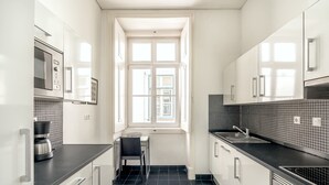 A modern kitchen with white cabinets, a black countertop, and a window with a view of buildings.
