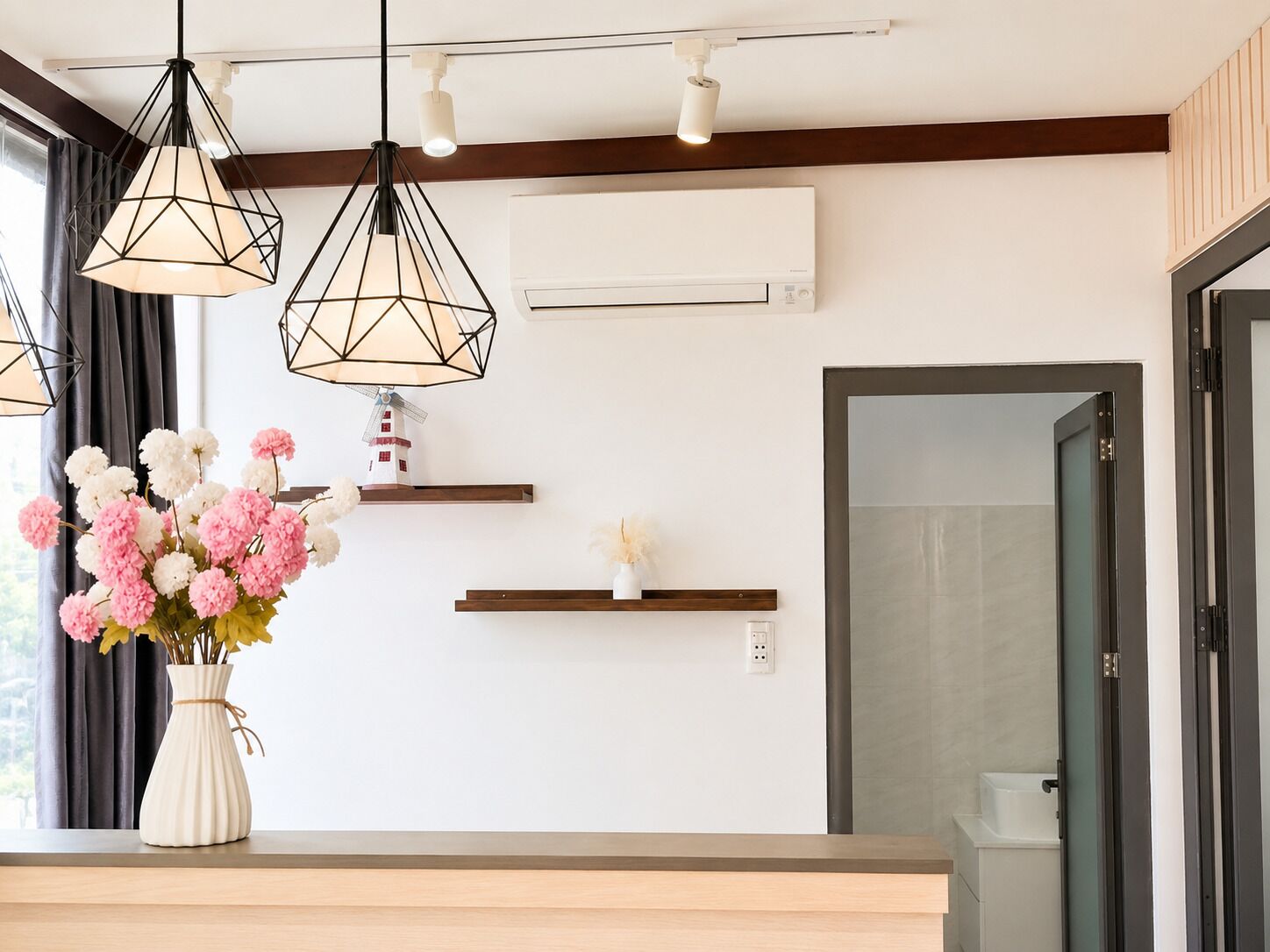 Ein modernes Interieur mit Pendelleuchten, einer Blumenvase und einer Windmüllerdeko auf einem Regal.
