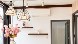 A modern interior with pendant lighting, a vase of flowers, and a windmill decoration on a shelf. - M Home Saigon (Ho Chi Minh City)