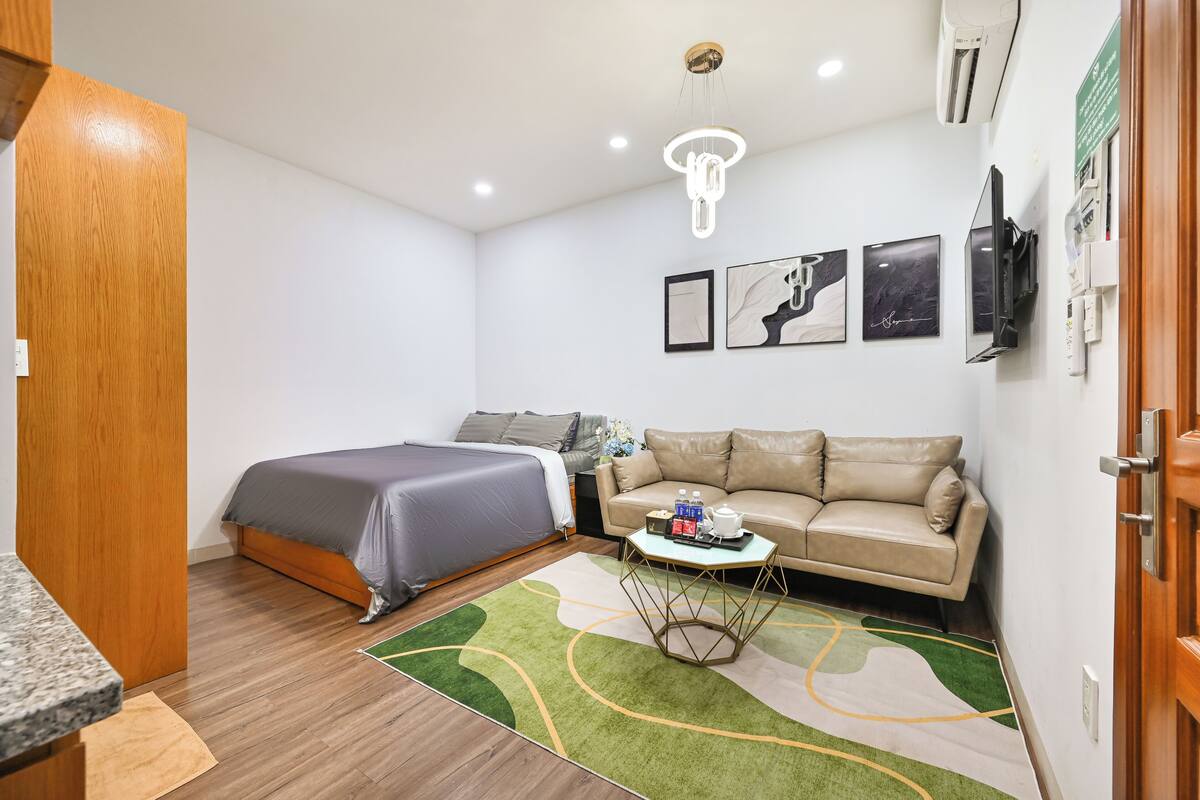 Ein Zimmer mit einem Bett, einer Schlafcouch, einem kleinen Tisch mit Gegenständen, einem Wand-Fernseher und einer Deckenleuchte.