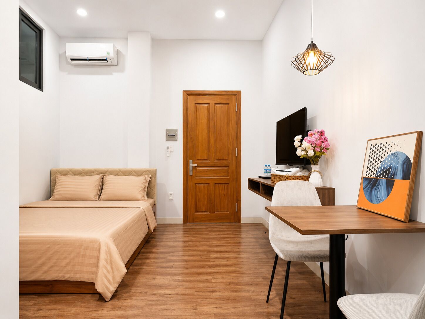 Un dormitorio con cama, escritorio, silla, televisor y puerta.