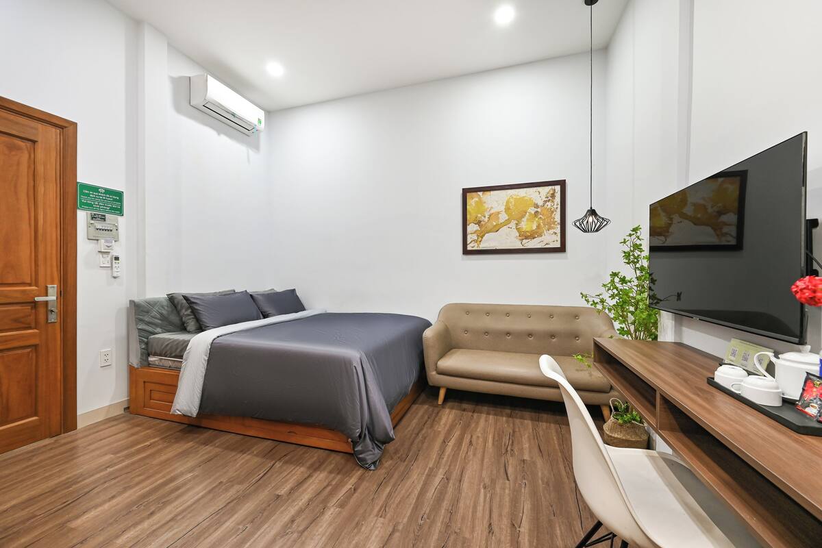 Ein modernes Hotelzimmer mit Bett, Sofa, Fernseher und Holzboden.