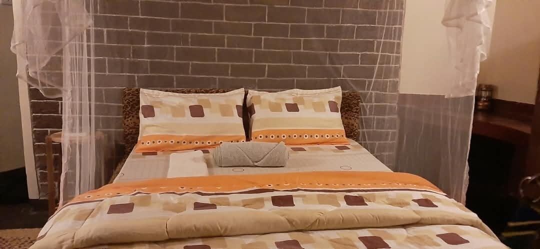 Una cama con una colcha estampada, dos almohadas y un pequeño bolso de mano.