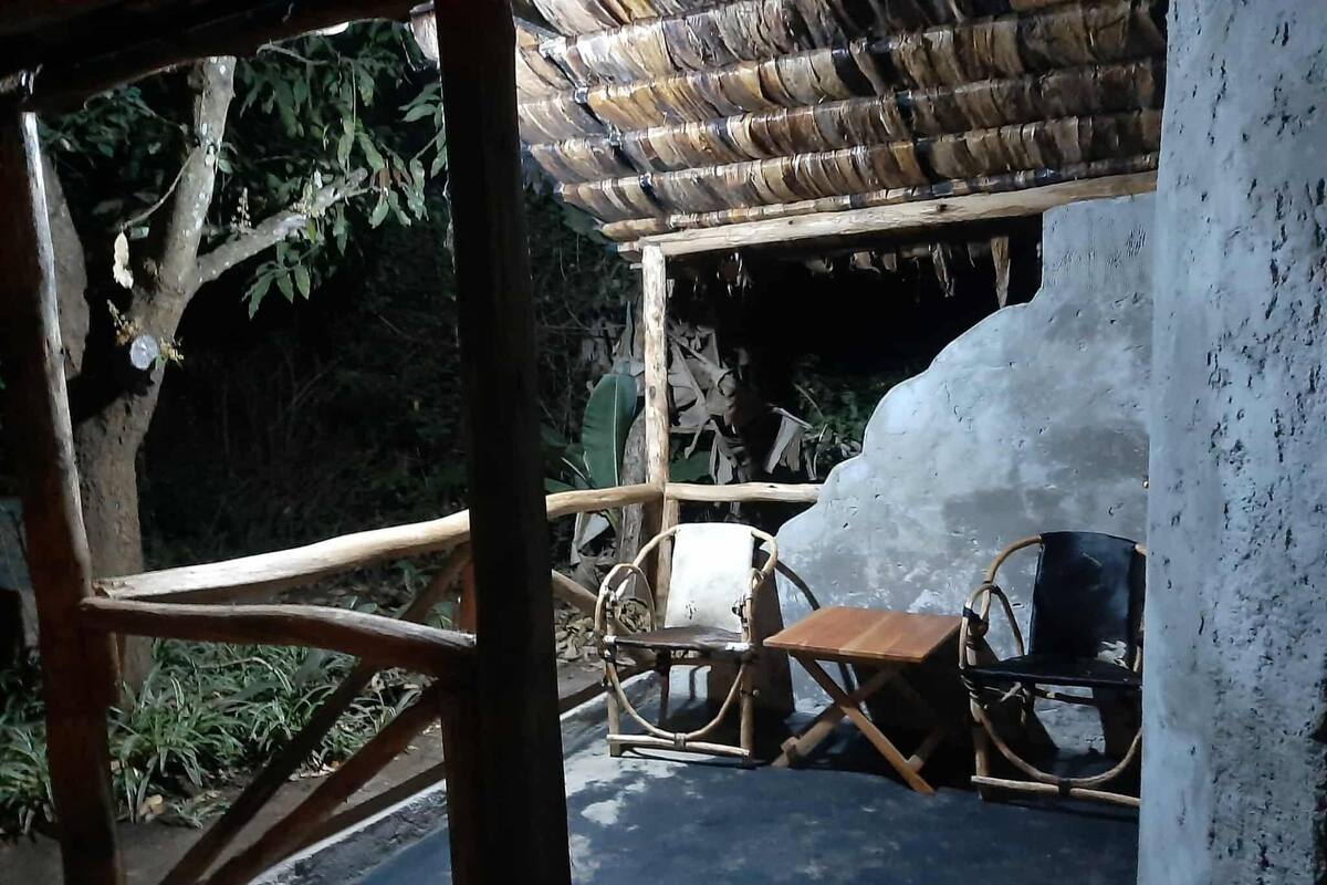 Una terraza de madera con techo de paja, una silla rústica y una gran escultura de hielo.