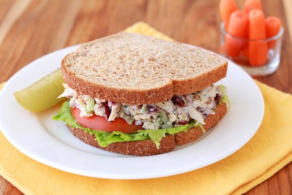 Un sandwich sur une assiette blanche, avec une serviette jaune en dessous.
