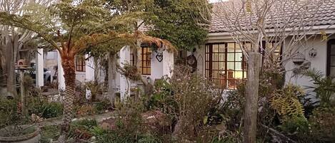 A traditional Japanese-style garden with a house featuring a tiled roof and wooden windows.