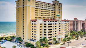 A multi-story hotel with a central courtyard, a pool area, and a view of the beach. - Parrot-ise by StayMareni - Oceanfront Suite (Myrtle Beach)