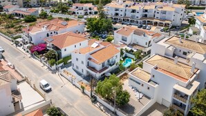 A residential area with white buildings, red-tiled roofs, and a swimming pool.
