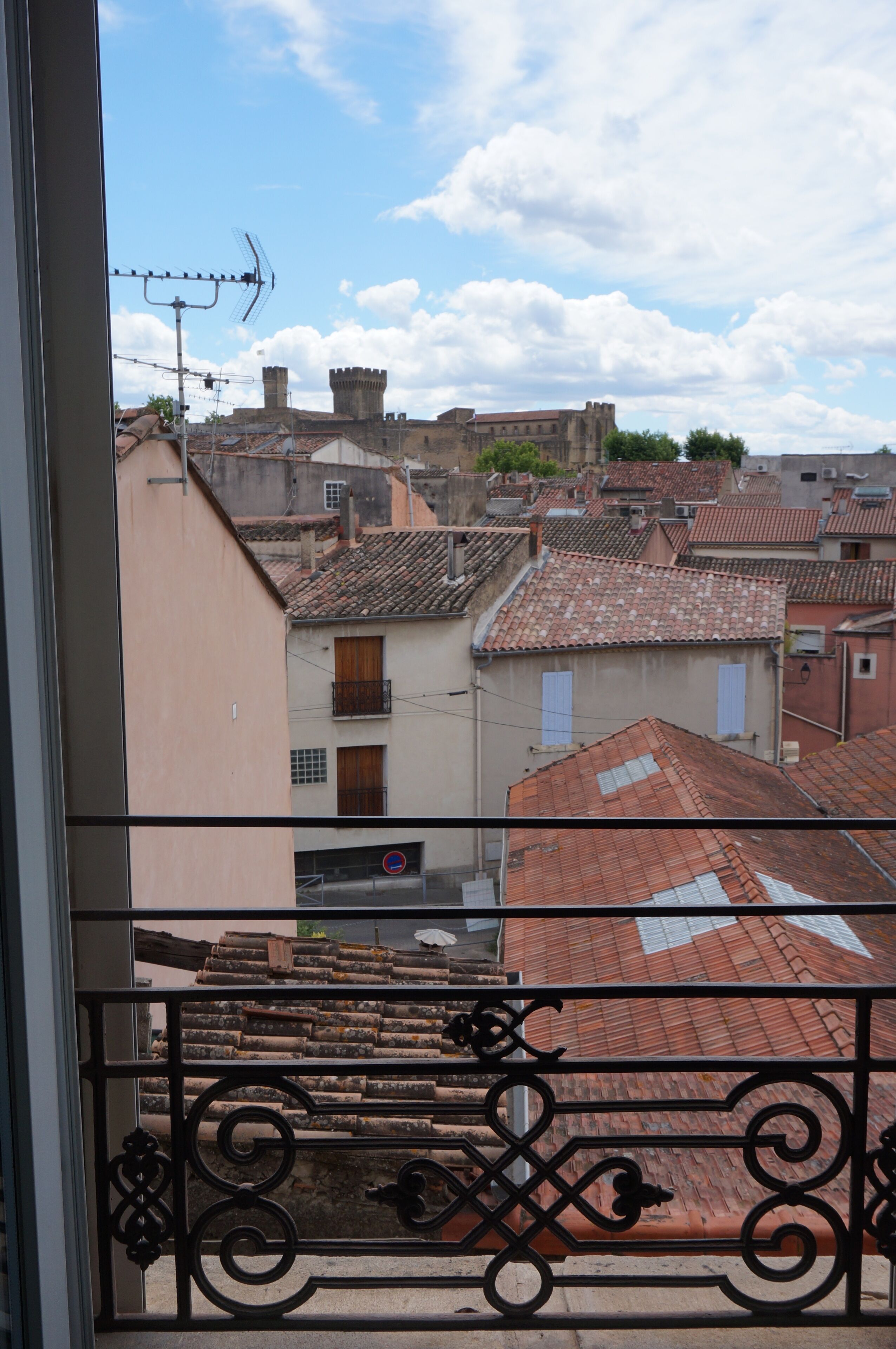 Vista de edificios con tejados de tejas rojas y una estructura similar a un castillo al fondo.