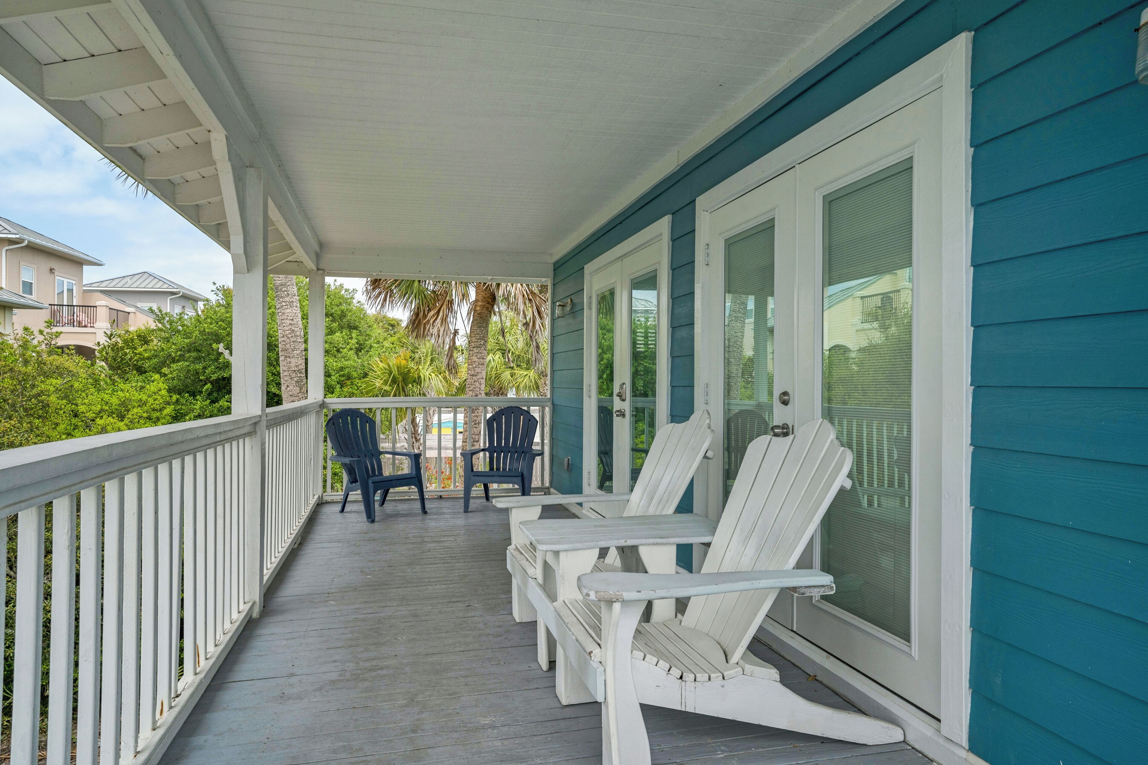 A covered porch with white railings and a blue exterior wall.