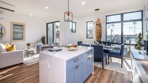 A modern kitchen with a central island, blue cabinets, and a dining area with a view.