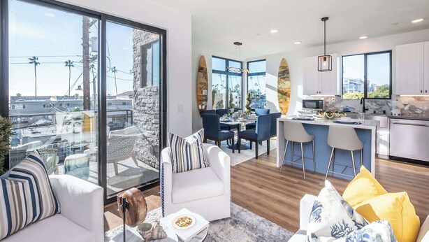 A modern living room with a glass wall, a dining area, and a kitchen.