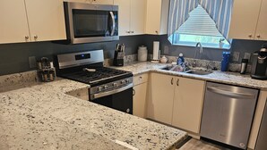 A kitchen with a granite countertop, stainless steel appliances, and a window with a view of the outdoors. - Charming 2-bedroom house in fabulous The Villages with AC (The Villages)