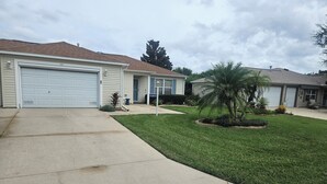 A residential area with houses, a driveway, and a well-maintained lawn. - Charming 2-bedroom house in fabulous The Villages with AC (The Villages)