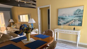 A dining area with a wooden table, blue placemats, and a vase of flowers. There is a white chair and a sofa in the background. - Charming 2-bedroom house in fabulous The Villages with AC (The Villages)
