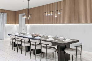 A modern dining area with a long table set for six, surrounded by six chairs.