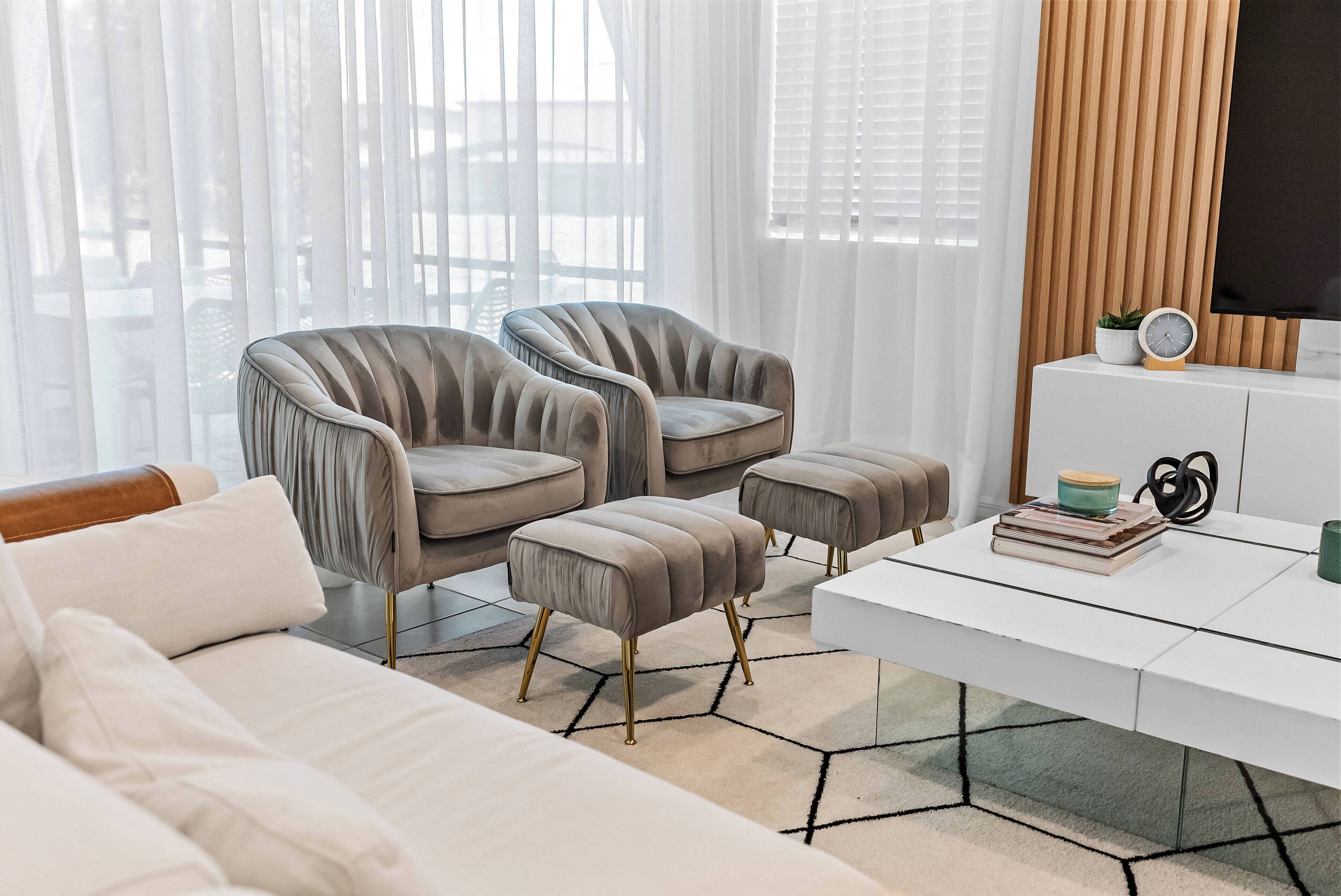 Una sala moderna con un sofá, dos sillones y una mesa de centro.