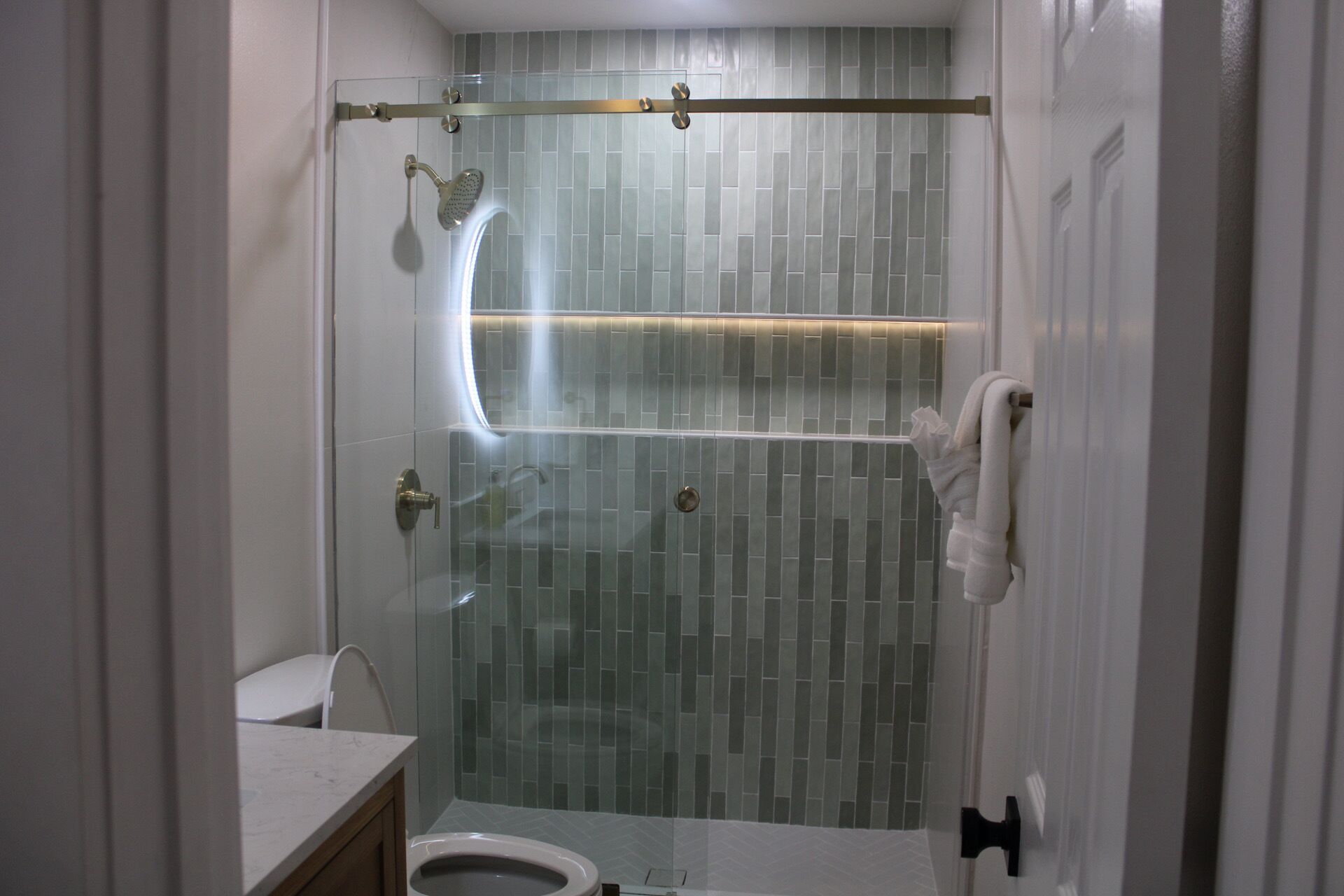 A modern bathroom with a glass-enclosed shower, a toilet, and a sink.