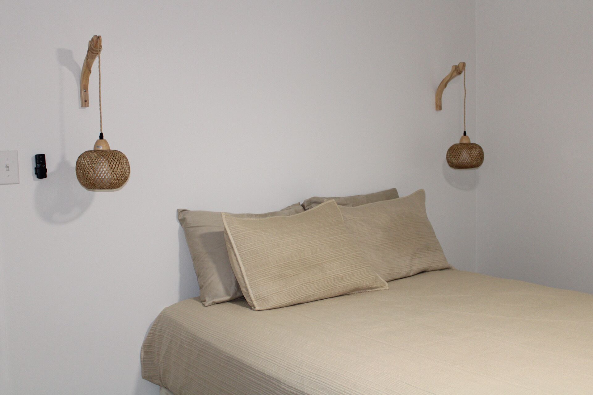 A bedroom with a bed, two pillows, and two wall-mounted lamps.