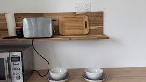 A kitchen area with a microwave, toaster, wooden cutting board, and two bowls on a wooden countertop. - Cosy studio in quiet location, Questembert town center (Questembert)