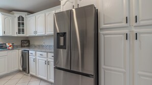 A kitchen with white cabinetry, stainless steel appliances, and a tiled floor.