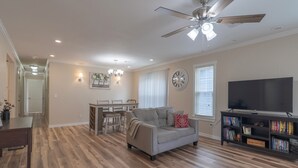 A spacious living room with a ceiling fan, a television, and a bookshelf.