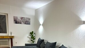 En moderne stue med en hjørnesofa, et lille hvidt bord og en radiator.