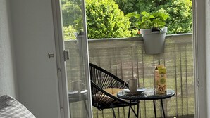 Et værelse med en seng, en stol og et bord med en potteplante samt en karton mælk.
