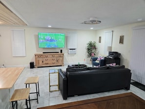 A living room with a television, a sofa, a coffee table, a dining table, and a plant. - Entire Waterfront Property on the Hillsborough River .Sleeps up to 14 Guests!!! (Tampa)
