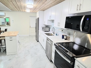 A modern kitchen with white cabinets, stainless steel appliances, and a wooden ceiling. - Entire Waterfront Property on the Hillsborough River .Sleeps up to 14 Guests!!! (Tampa)