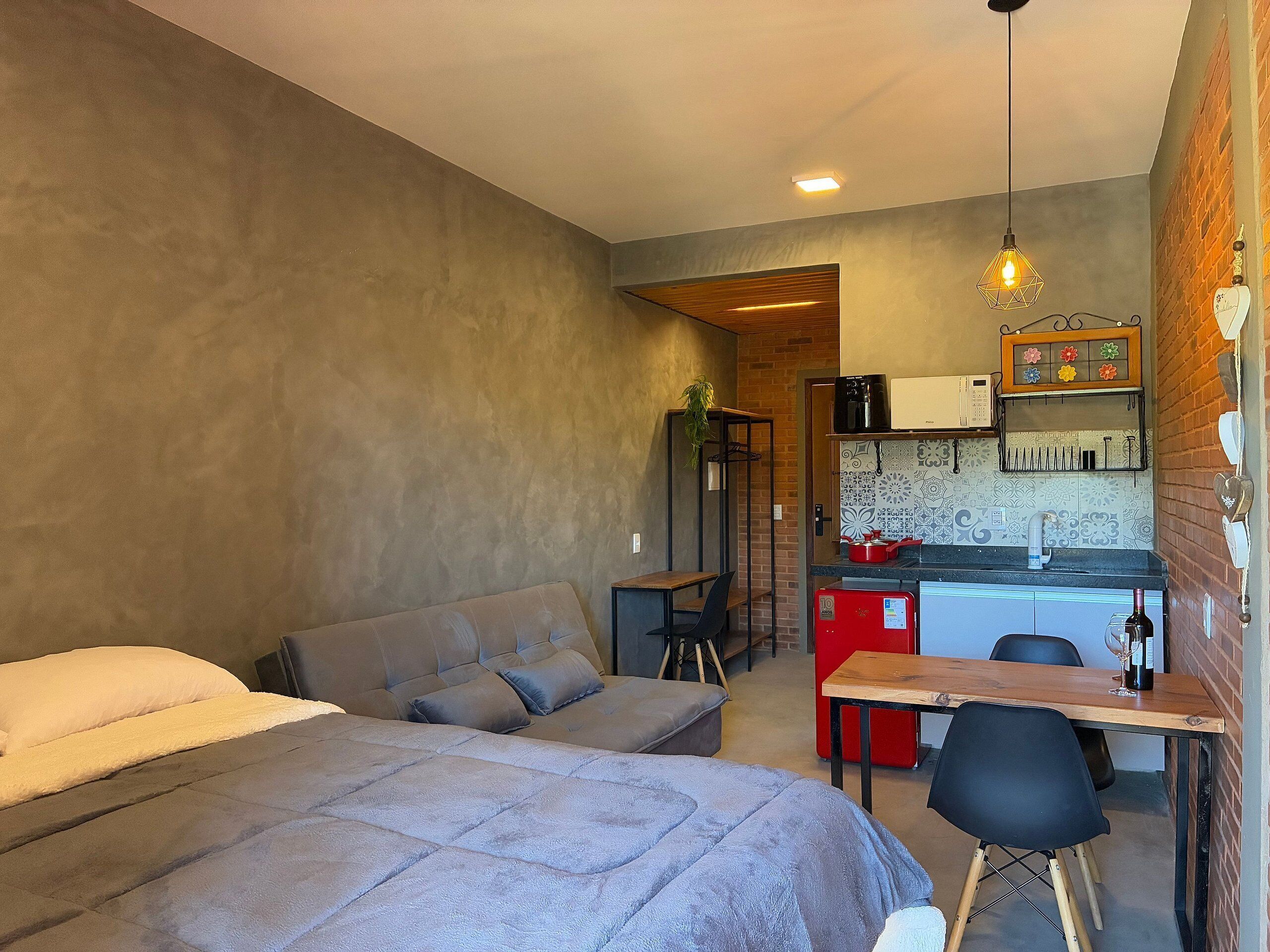 A compact room with two beds, a small kitchenette, and a dining area.