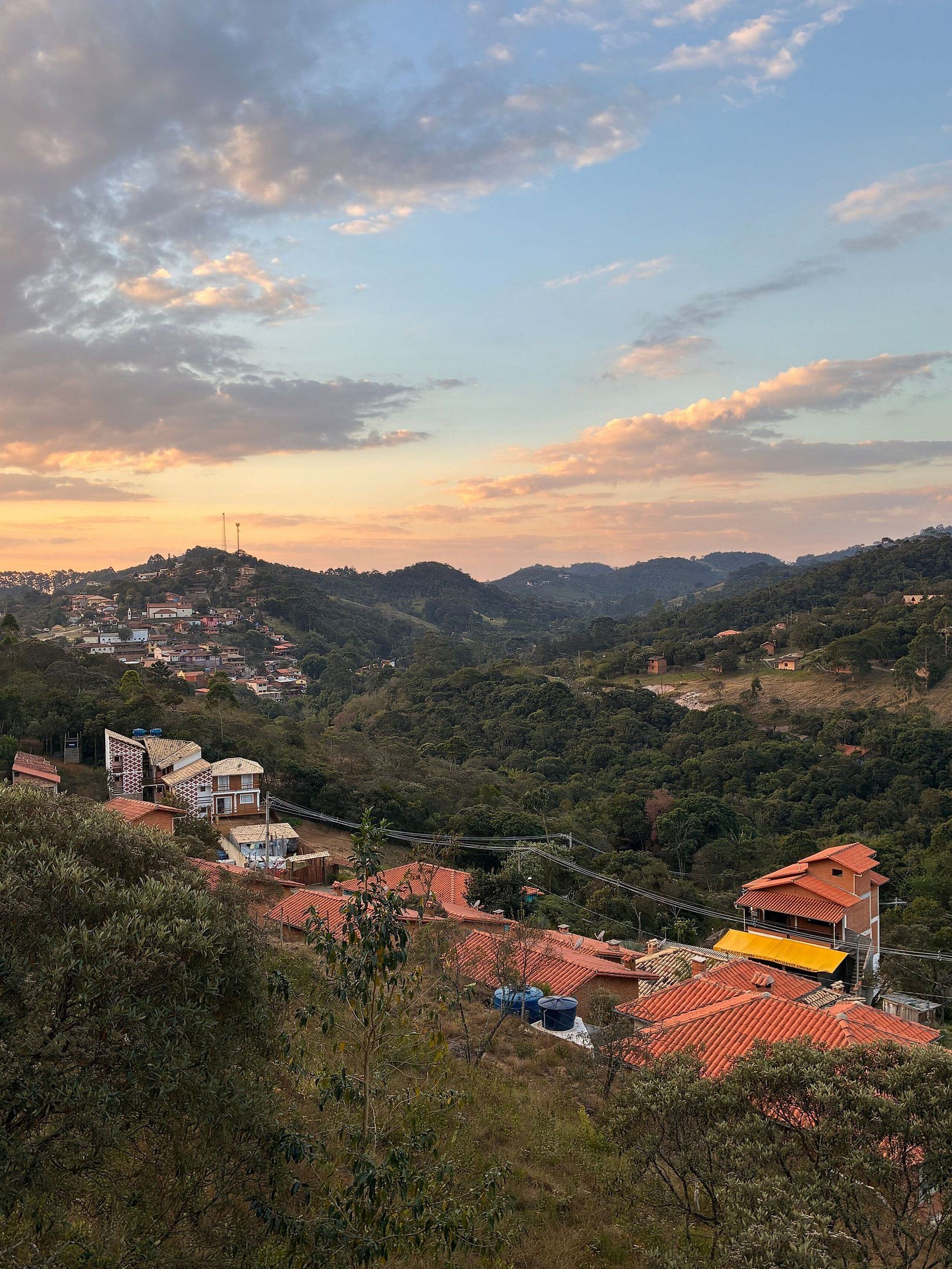 Un pueblo en una ladera con edificios, una estructura destacada de techo amarillo y una línea de electricidad.