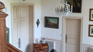 Eine prächtige Treppe führt zu einem Raum mit einer Chandelier, einem Gemälde und einer Heizung.