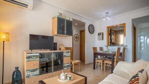A living room with a TV, a cabinet, a dining table with chairs, and a sofa.
