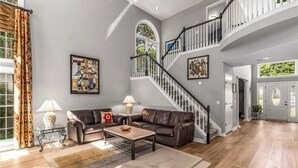 Un salon spacieux avec un escalier, des canapés en cuir et une grande fenêtre.