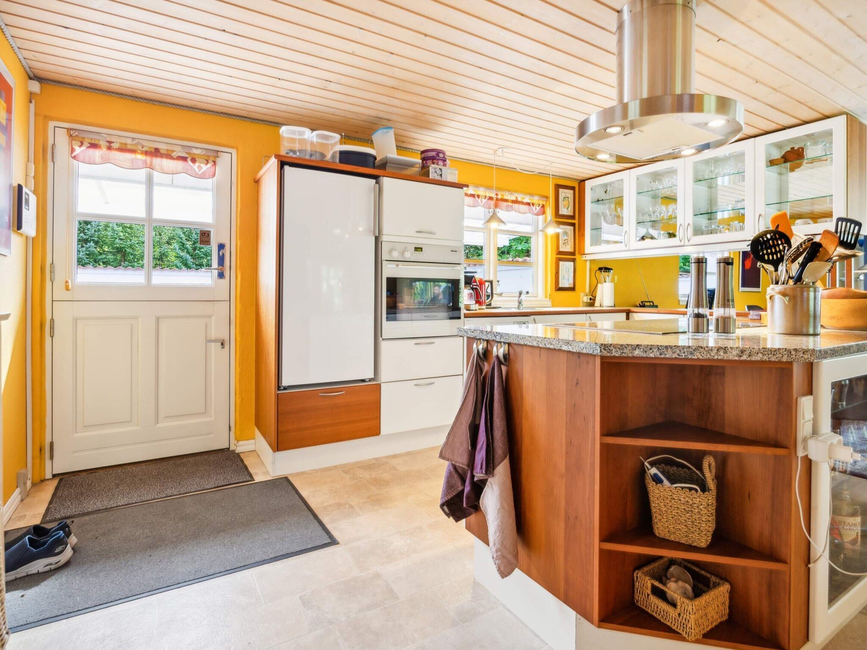 Une cuisine moderne dotée d’un îlot central en bois, d’un four encastré et d’un réfrigérateur.