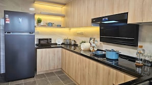 Eine moderne Küche mit einem Edelstahl-Kühlschrank, einer Mikrowelle, einem Herd und Holzschränken.
