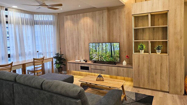 Ein modernes Wohnzimmer mit Flachbildfernseher, Holzwandverkleidung, Deckenventilator und Essbereich mit Tisch und Stühlen.