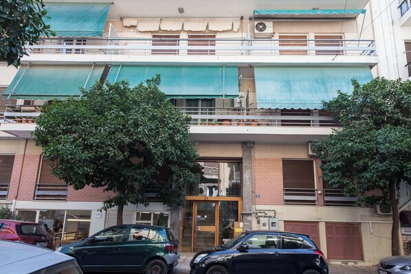 A two-story building with a green awning, a visible entrance, and a number '30' on the door.