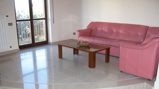 A living room with a pink leather sofa, a wooden coffee table, and a tiled floor.