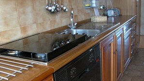 A kitchen with a stainless steel sink, wooden cabinets, and a built-in oven.