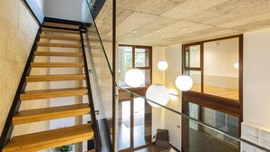 Un escalier moderne avec des rampes en verre, des marches en bois et des luminaires suspendus.