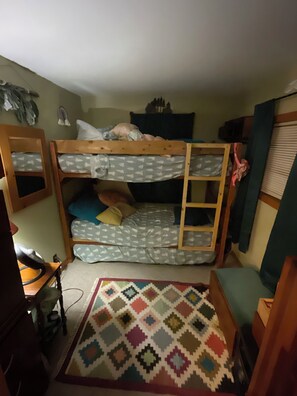 A bunk bed room with a desk and a patterned rug.