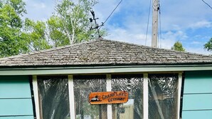 A small, single-story building with a sign reading "Grand Lake Getaway." - Charming 2-bedroom cabin on lake near Duluth MN with Air Conditioning (Saginaw)