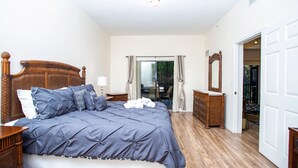 A bedroom with a large bed, wooden headboard, and a dresser.